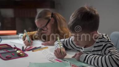 小白种人男孩和他的同学坐在一起，写在练习本里，说话。 两名同学